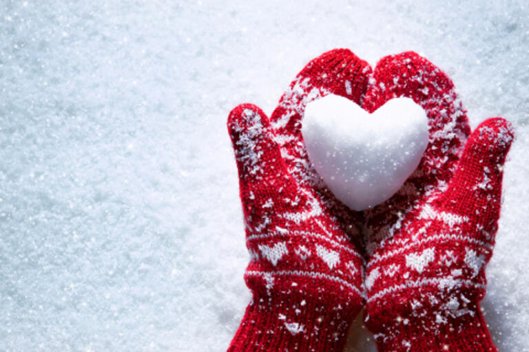Heart made of snow in two gloved hands