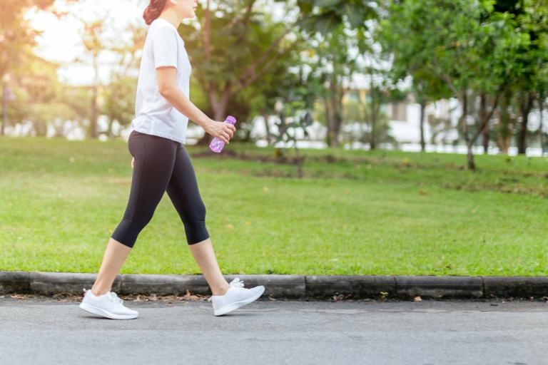 Woman walking outside, holding a water bottle