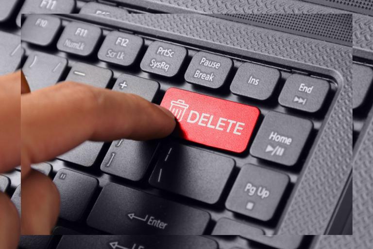 Finger hovering over the delete button of a computer keyboard