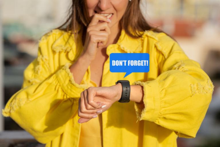 Woman in yellow top looking at her watch, with the words don't forget