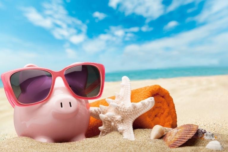 Piggybank in sunglasses relaxing on a beach next to a starfish
