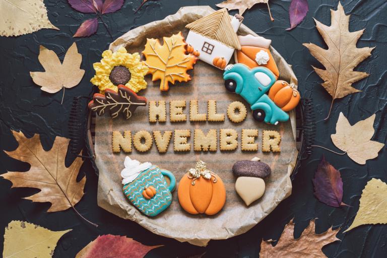 Log stump surrounded by Autumn leaves with the words Hello November