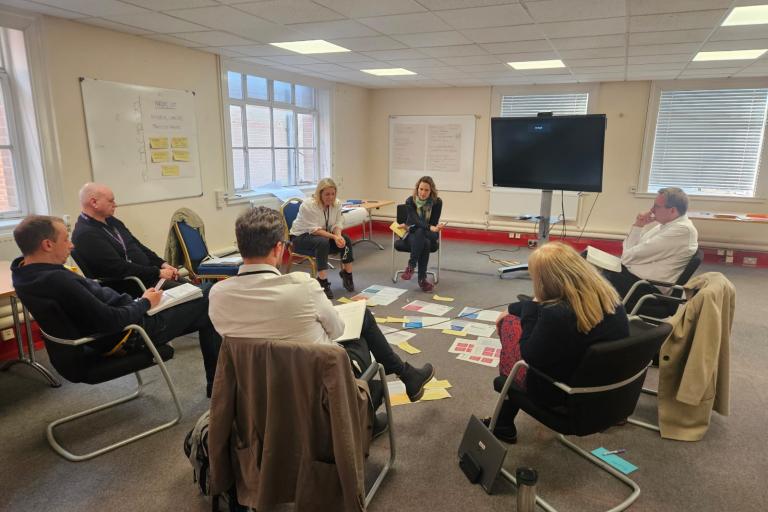 Corporate Leadership Team members sitting in a circle of a room in conversation