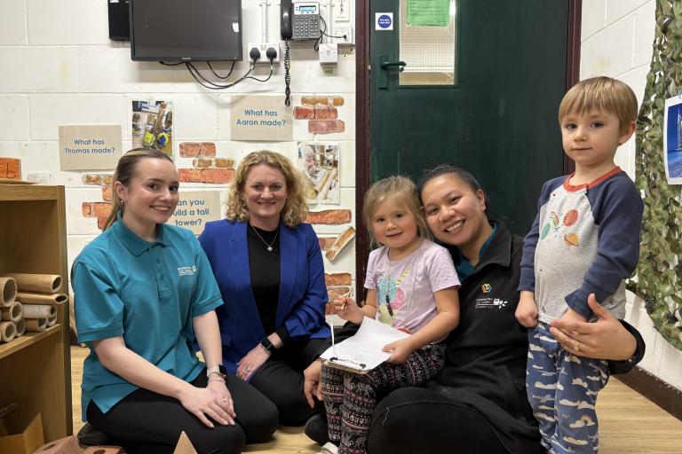 Photo of Cllr Louise McKinlay with two adults and two children, smiling and in a school setting