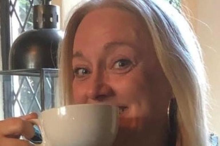 Tracy holding up a mug of tea in a white cup