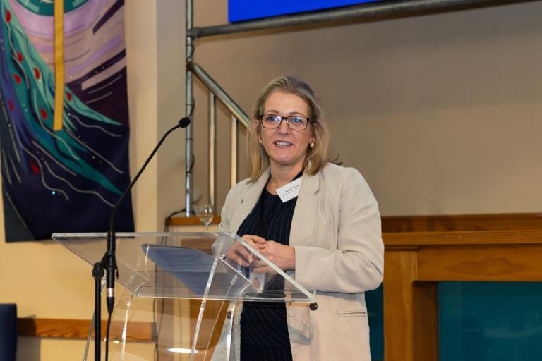 Nicole standing in front of a lectern on a stage 