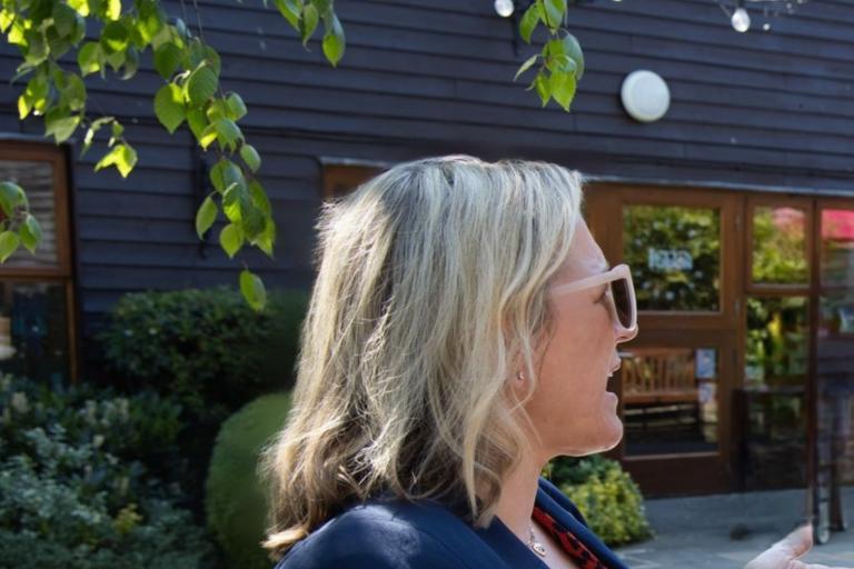 Informal photo of Nicole standing in the sun in conversation 