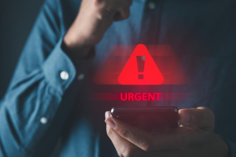 Man holding a phone with a hazard sign floating above it and the words urgent