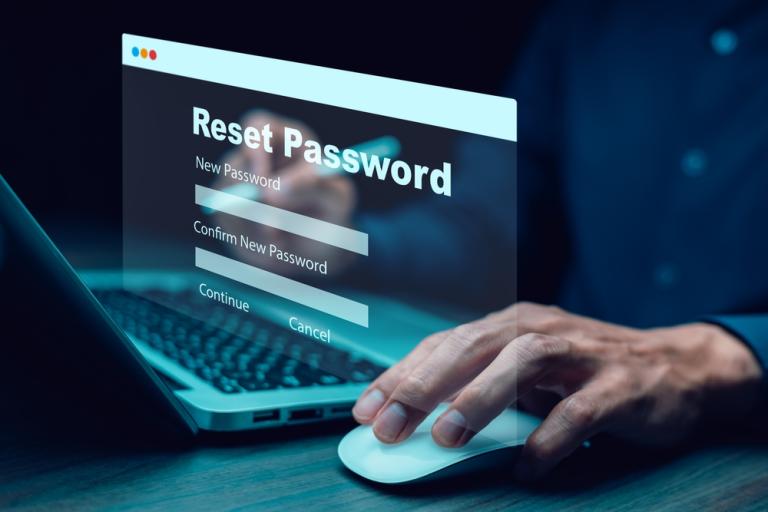 Fingertips at a keyboard with the words reset password floating above it