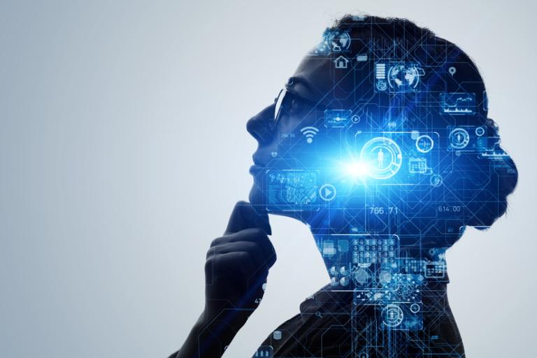 Woman wearing glasses, looking up and holding her chin. Projected over her face in blue are some circuit board and cog images