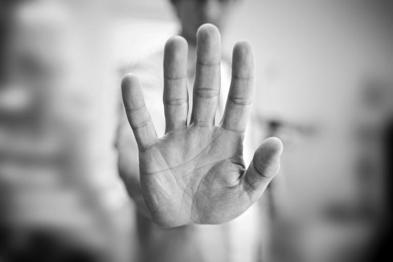 Black and white photo of a hand held up in a stop sign