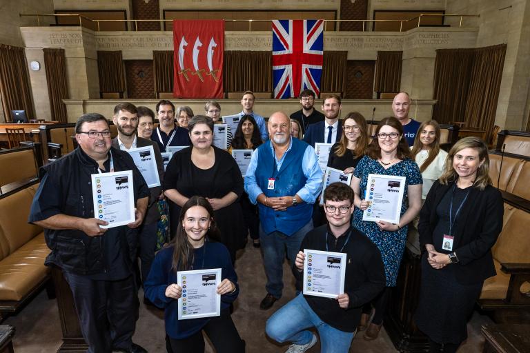 Photo of staff in the Council Chamber holding up their certificates