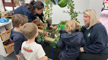 Staff and children sitting around a desk at Banana Moon nursery in Billericay