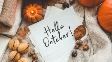 The words hello October on a white piece of paper, sitting on top of some hessian and surrounded by pumpkins, nuts and seeds