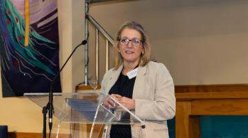 Nicole standing in front of a lectern on a stage 
