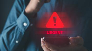 Man holding a phone with a hazard sign floating above it and the words urgent