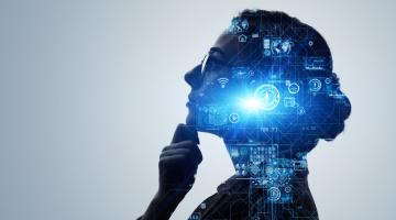 Woman wearing glasses, looking up and holding her chin. Projected over her face in blue are some circuit board and cog images