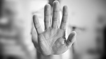 Black and white photo of a hand held up in a stop sign