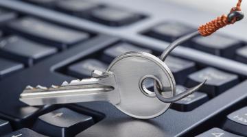 computer keyboard with silver fishing hook being dangled over it