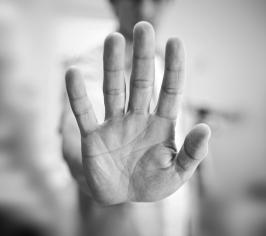 Black and white photo of a hand held up in a stop sign